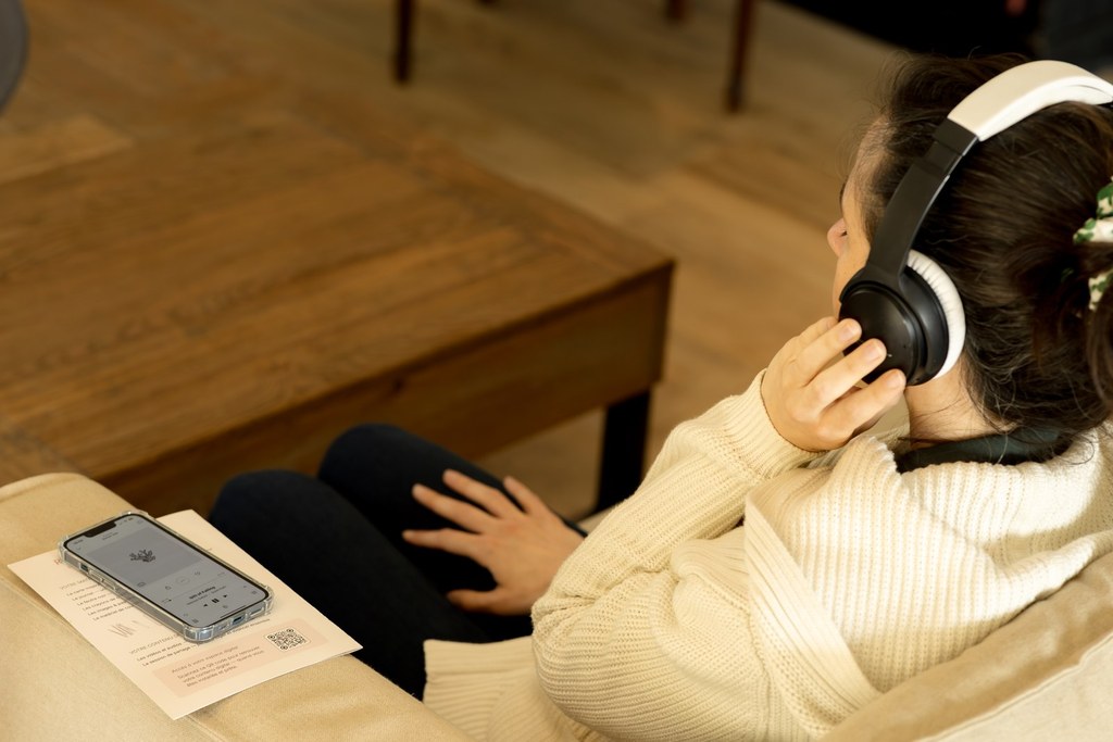Une femme, les yeux fermés et un casque sur les oreilles, écoute la méditation sur son téléphone