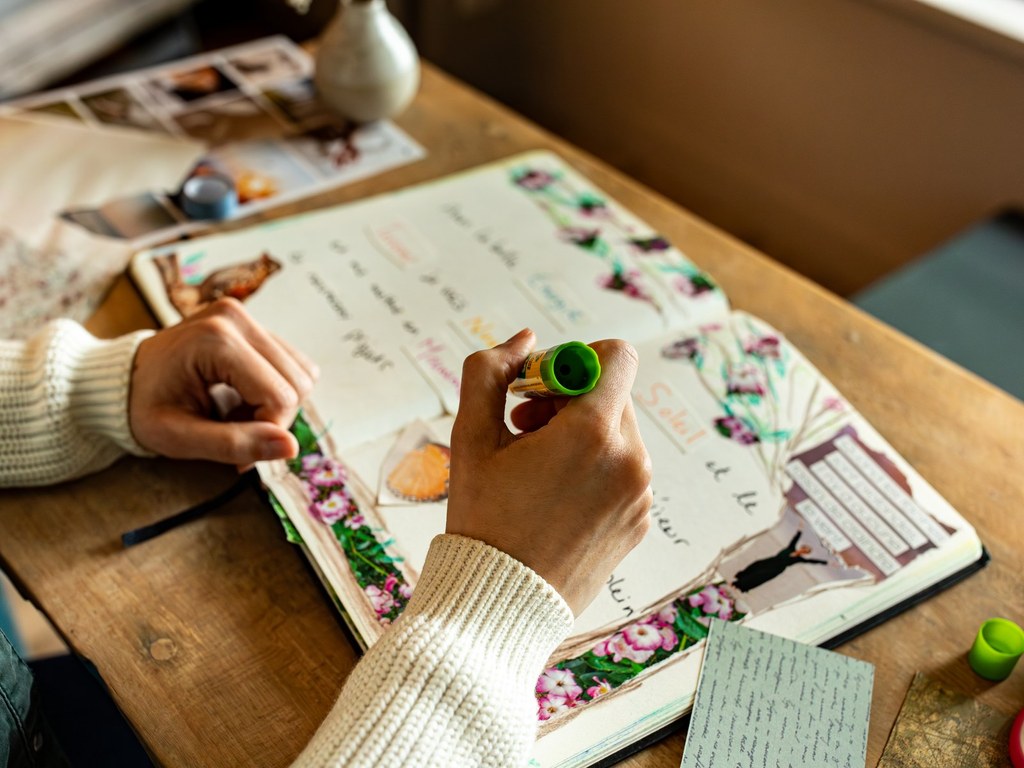 Un journal en cours de composition, avec des papiers colorés, des images découpées et de la colle sur la table